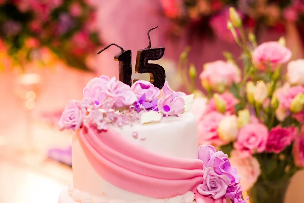 Bolo de 15 anos decorado com flores cor-de-rosa.